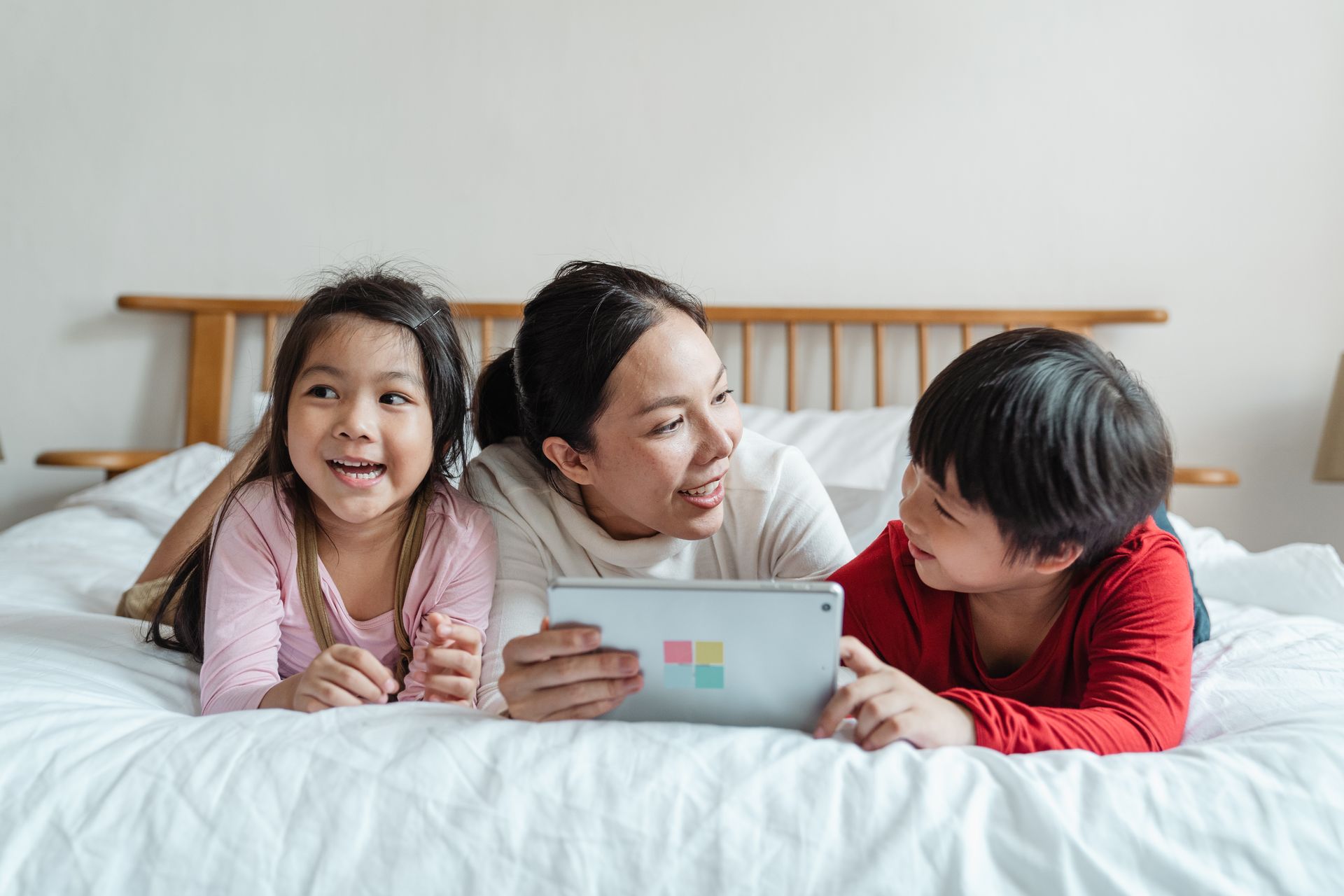 Eine Mutter lernt gemeinsam mit zwei Kindern an einem Tablet.